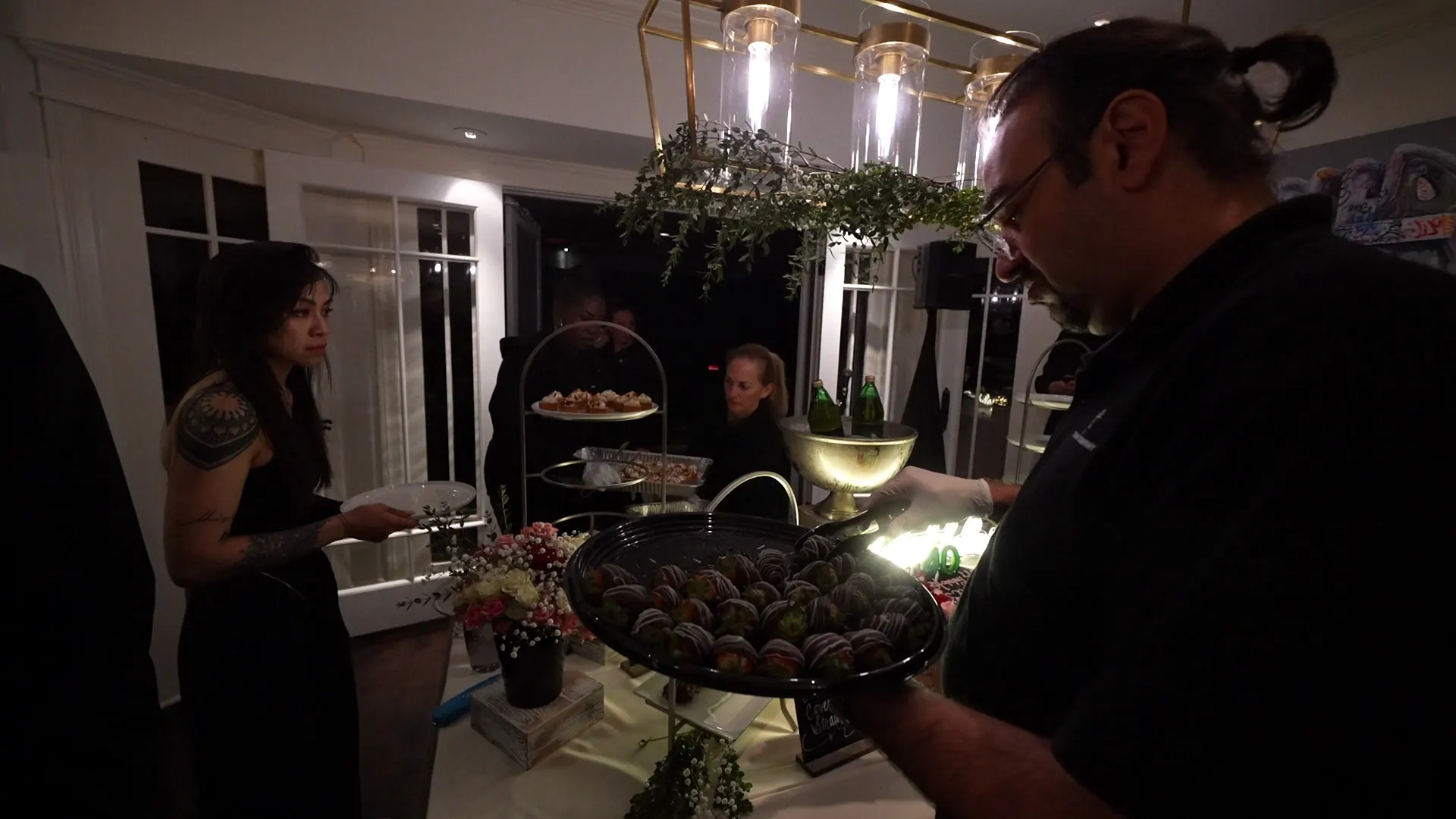 Server carrying a dessert platter past tiered sweets at a San Pablo reception