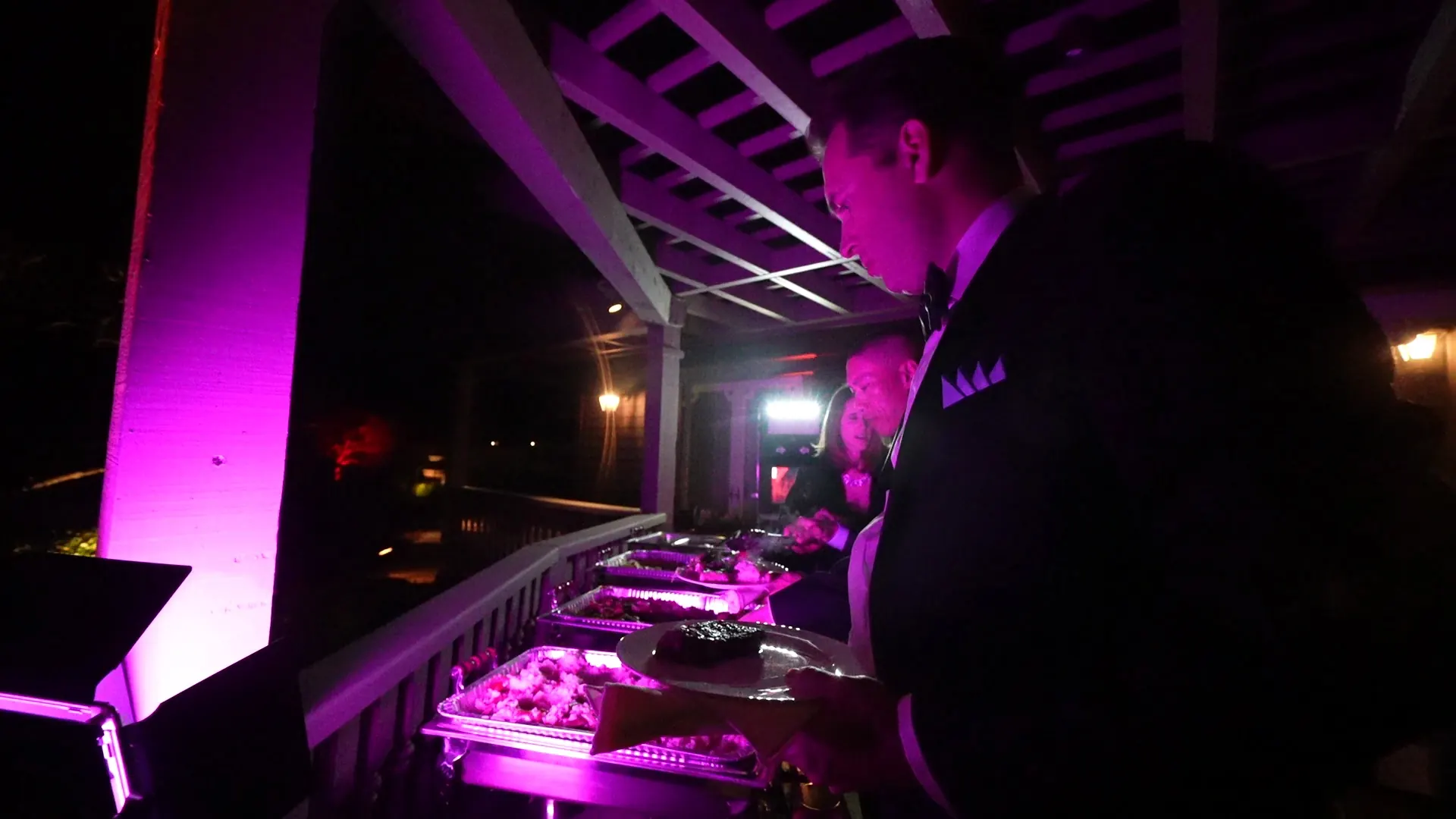 Attendant tending chafing dishes under magenta uplighting at a Richmond evening reception