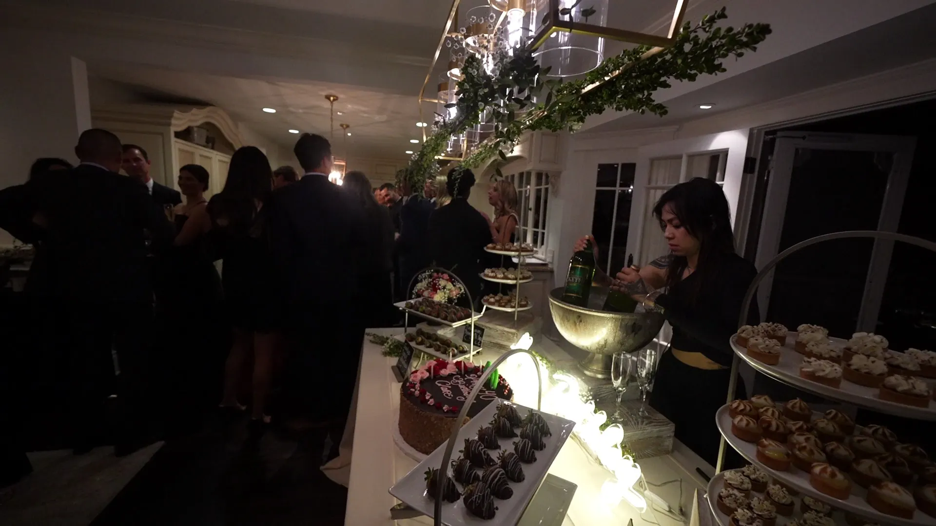 Greenery-draped dessert tier station with staff plating sweets at an Alameda reception