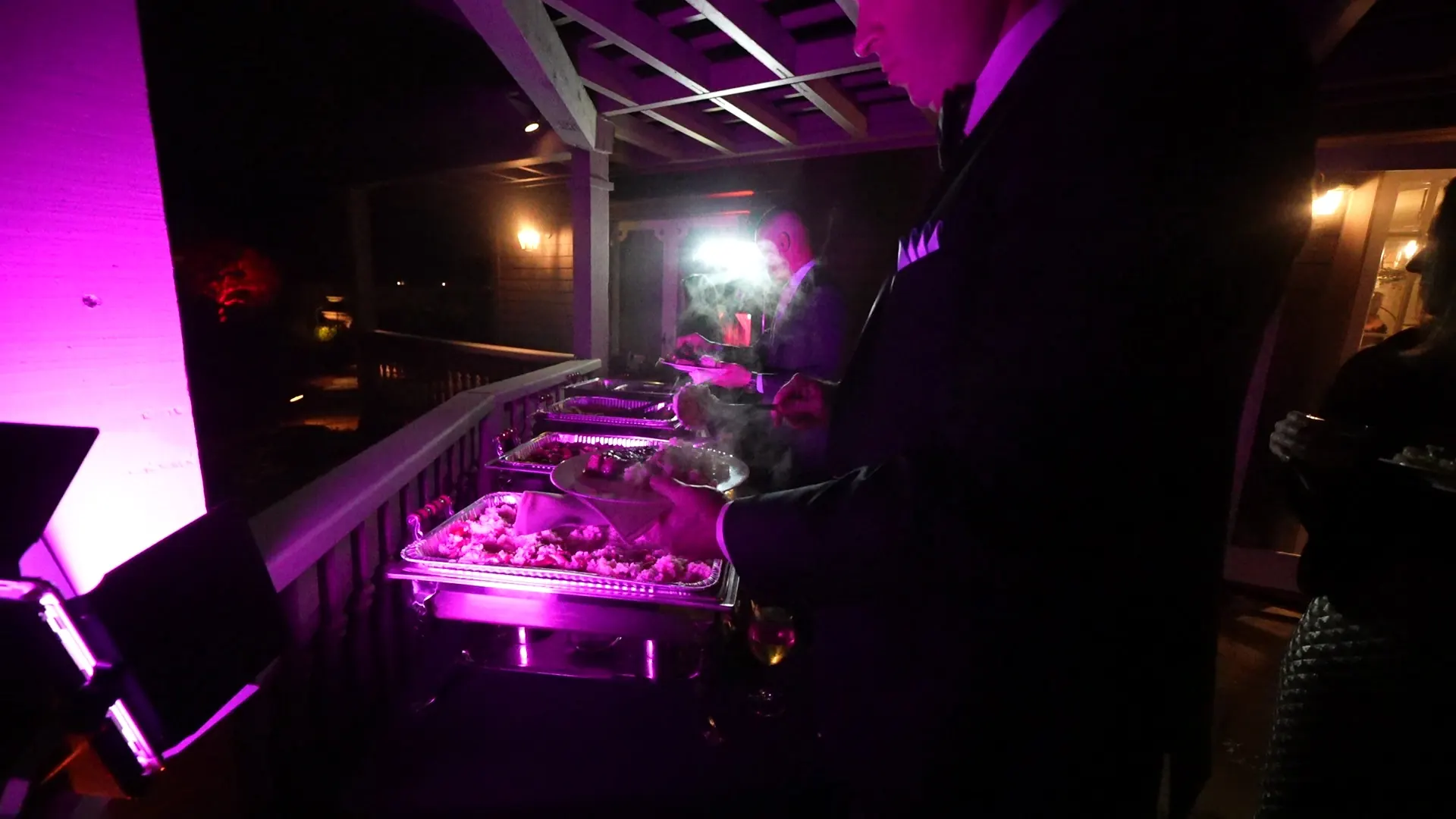 Chafing-dish buffet lit in magenta on a deck at a nighttime El Cerrito party