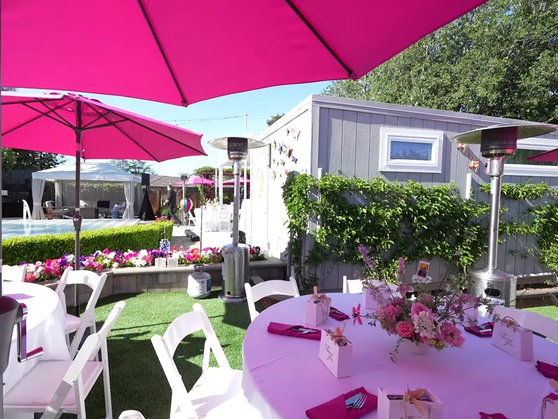 Backyard reception near Oakland with pink market umbrellas, florals and white folding chairs