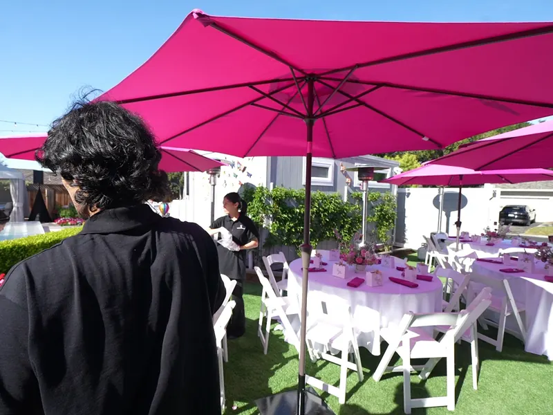 Guests seated at round tables under bright umbrellas at a Richmond outdoor party