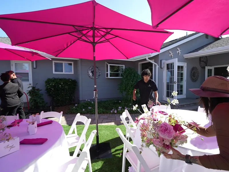 Catering staff placing florals on umbrella tables before a Richmond backyard event