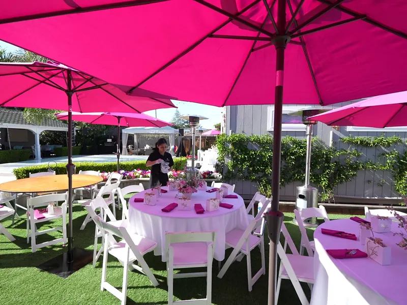 Round tables under market umbrellas set for a daytime Albany backyard lunch