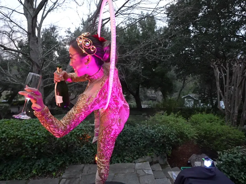 Aerial performer pouring champagne above the garden at an Albany celebration