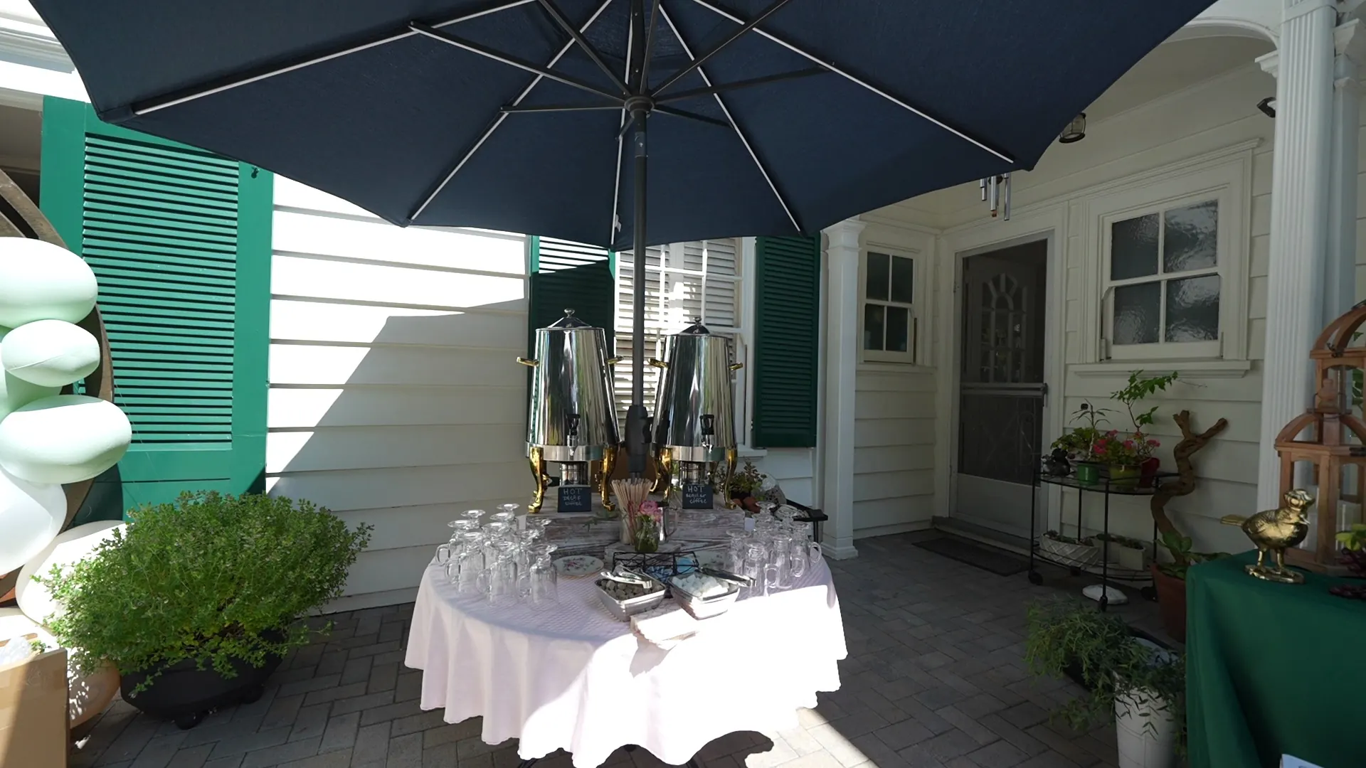 Silver coffee urns and glassware set on a linen table on a Piedmont brick patio