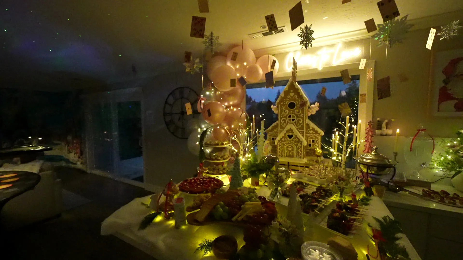 Warmly lit holiday dessert display with balloons and gingerbread centerpiece at a San Leandro party
