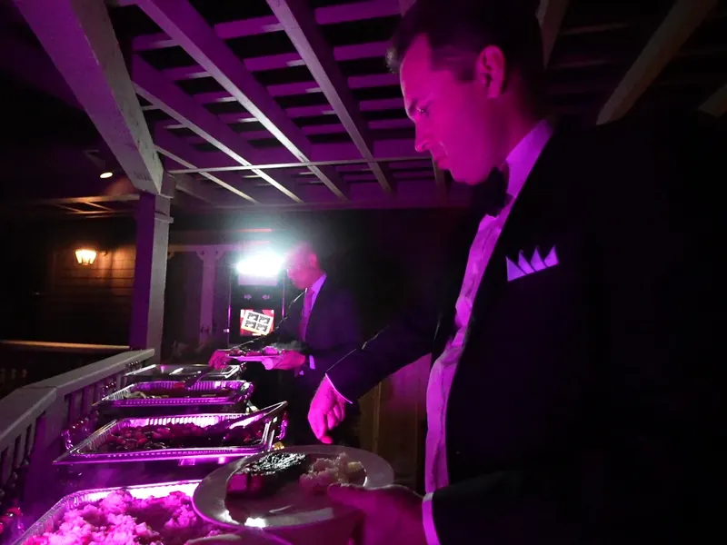 Attendant plating from a warmly lit deck buffet at a San Pablo celebration