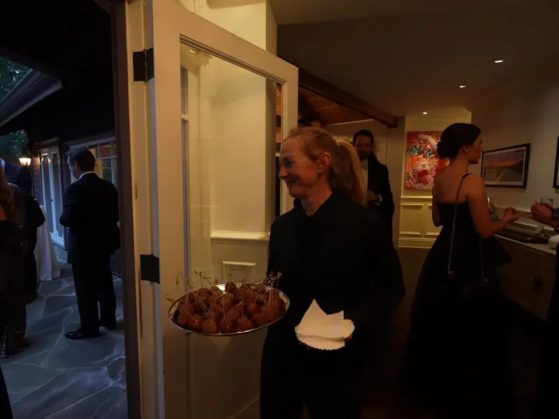 Server carrying a tray of hot appetizers through the doorway at an Alameda house party