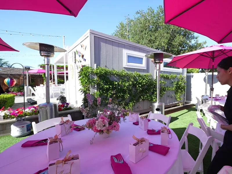 Umbrella tables set with guest favors and patio heaters for a Hercules celebration
