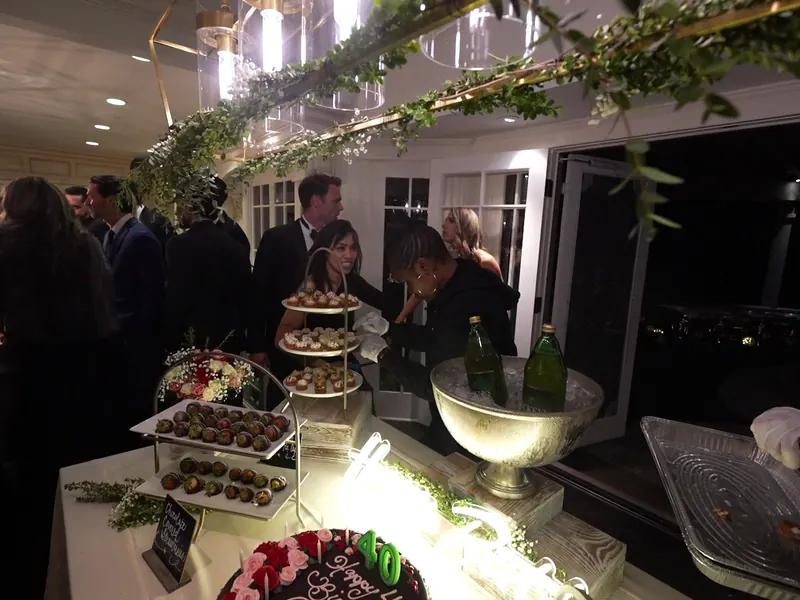 Guests gathered around a greenery-draped dessert and champagne display on a Piedmont patio