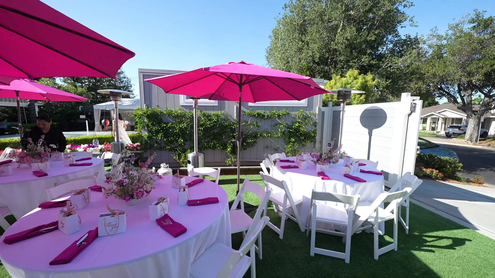 Round lunch tables with florals and pink napkins under market umbrellas at an Emeryville gathering