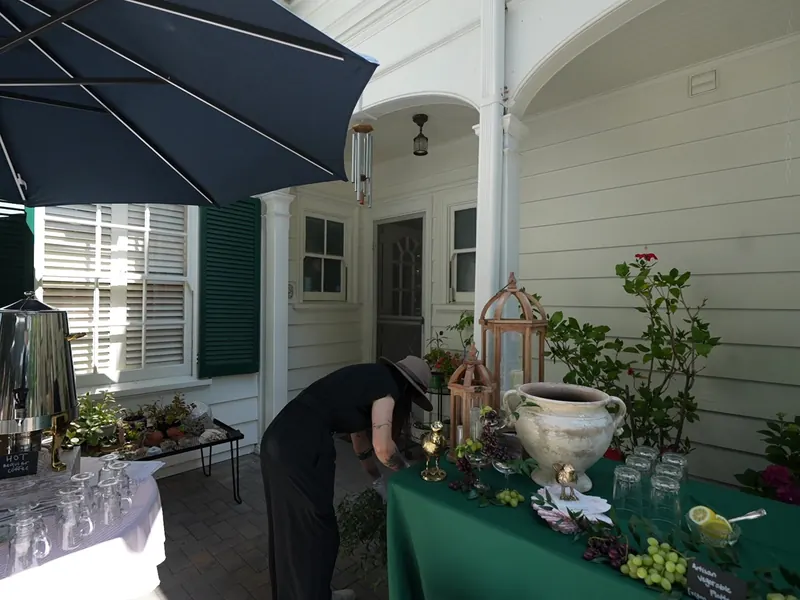 Appetizer and beverage table set under an umbrella on a covered Alameda porch