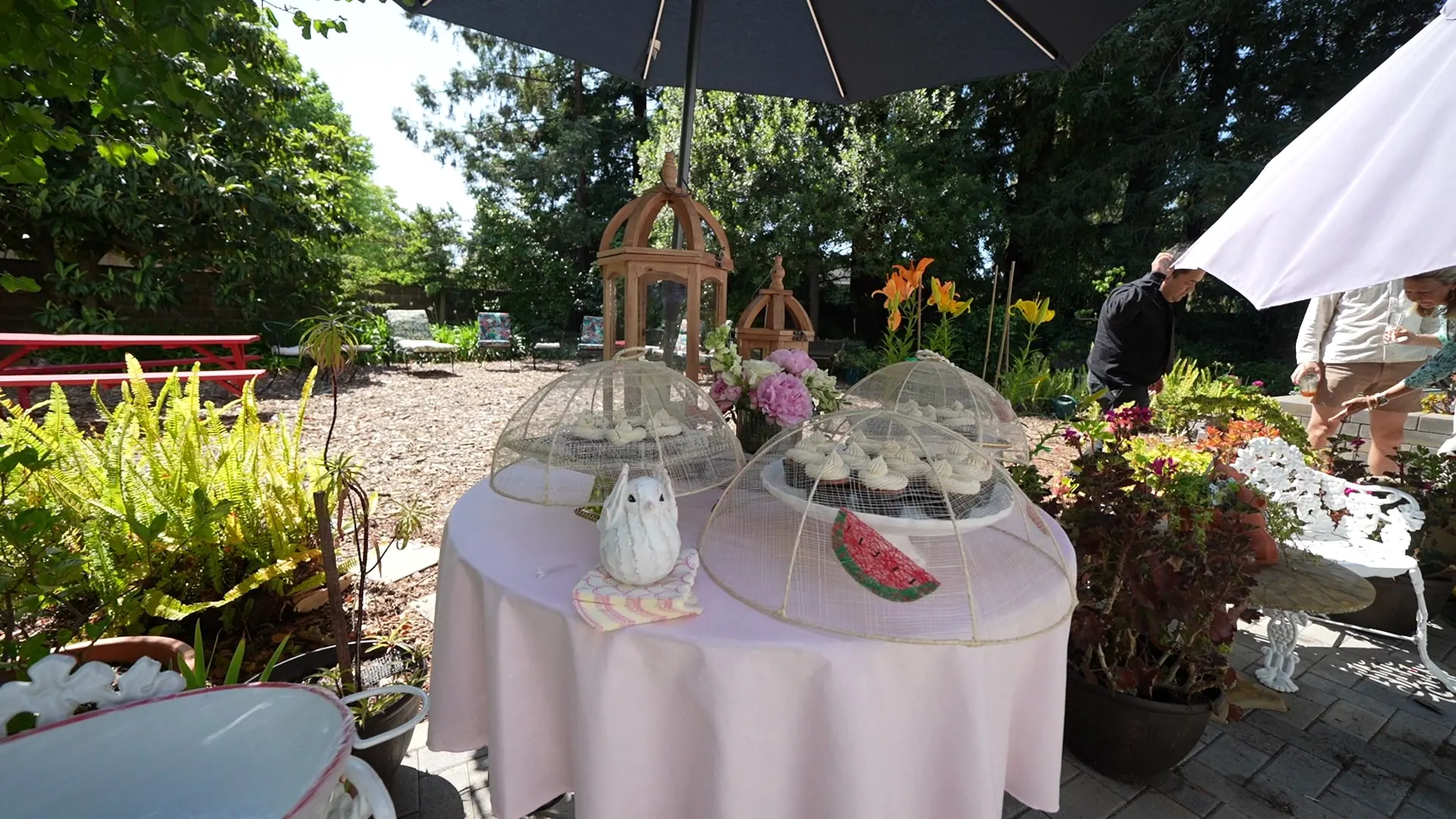 Garden dessert table with glass cloches and cupcakes under an umbrella at a Rodeo party