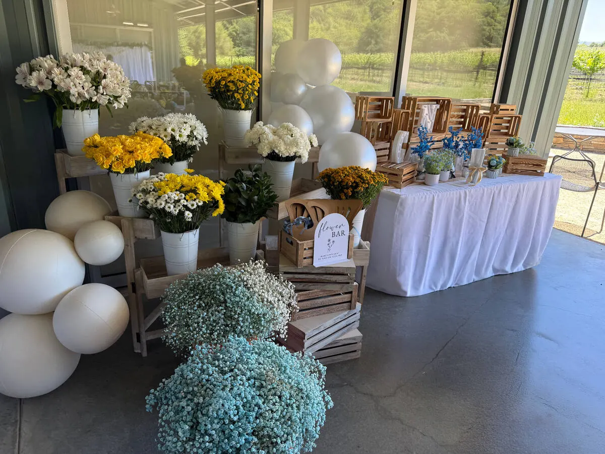 Bloom bar stocked with yellow roses, daisies and baby's breath beside ribbon and wrapping for guests — signature bloom bar for Oakland catering events