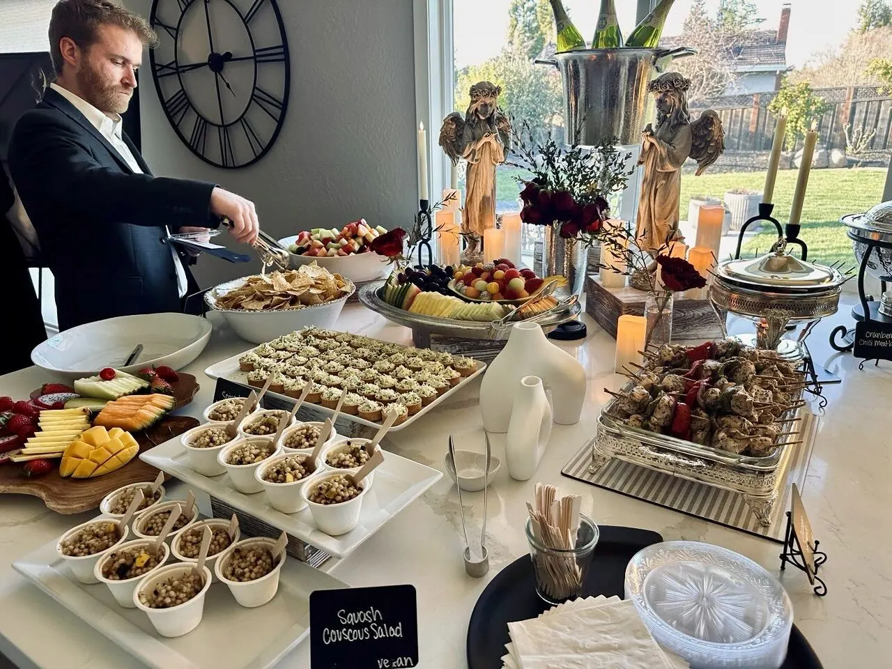 Polished starter buffet pairing herbed couscous salad, a fanned fruit platter and char-marked grilled skewers on crisp white linen — corporate starter spreads from Oakland catering