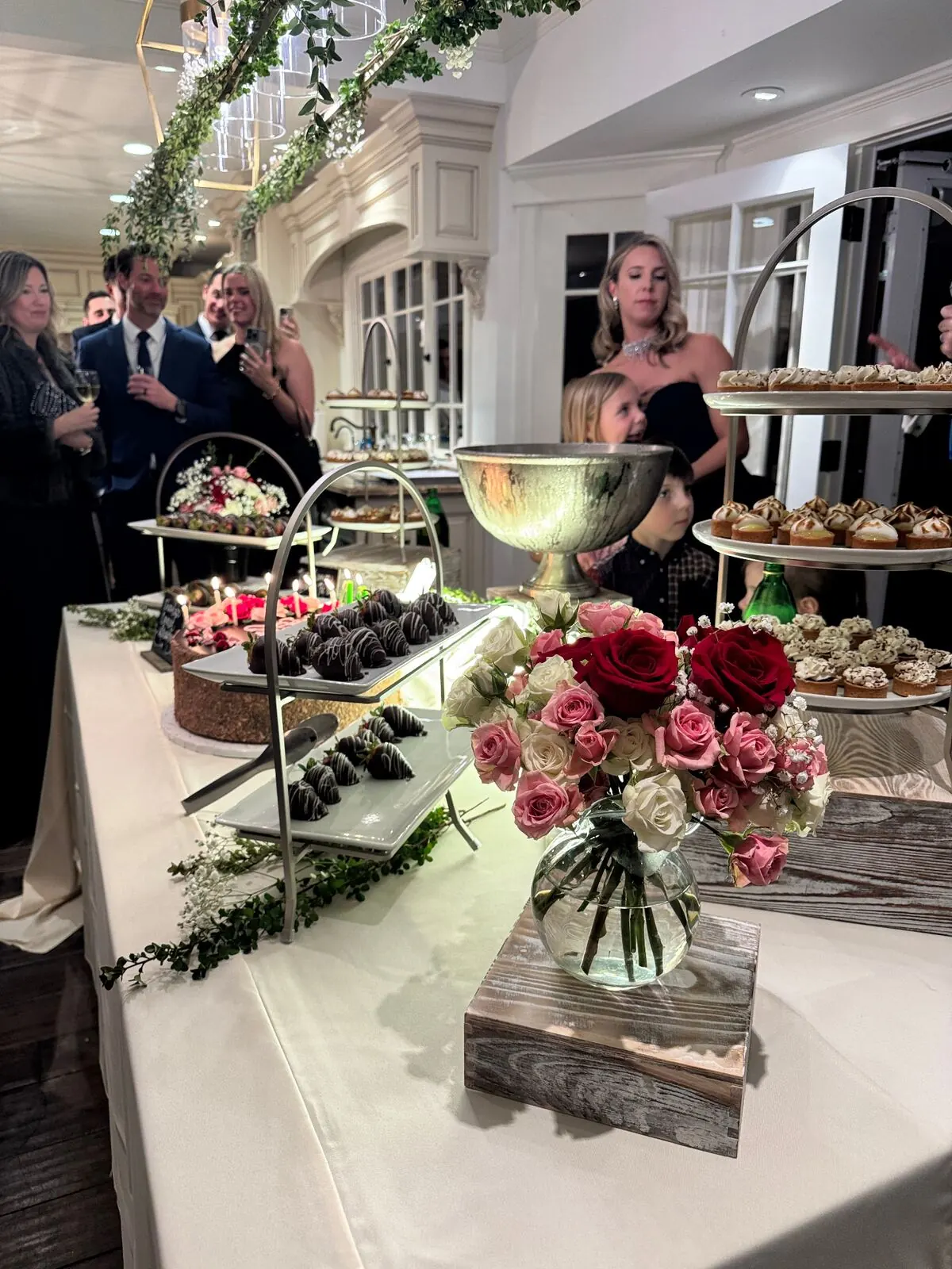 Wedding dessert table with tiered cake, mini pastries and chocolate-dipped strawberries at an Oakland reception by Oakland Catering Company