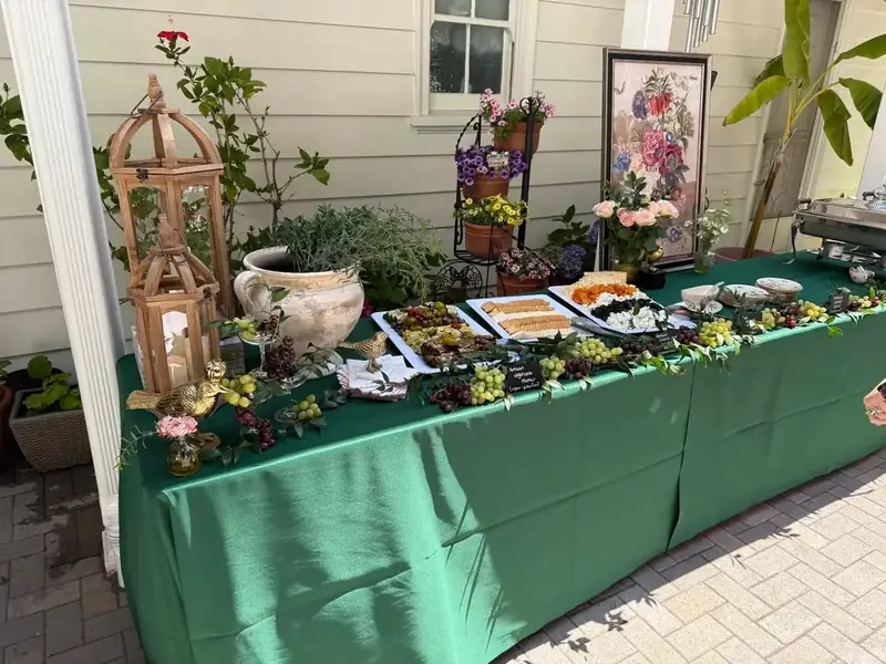 Oakland Catering Company display with catered appetizers, abundant grape clusters, decorative greenery, and vintage-style lanterns.